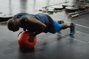 Adult man in gym doing push-up on a medicine ball, demonstrating strength and balance.